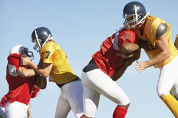 American football players tackling each other against clear sky
