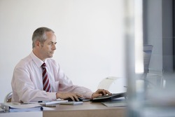 Middle aged businessman using computer at office desk