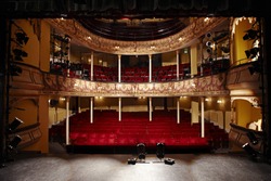 View of an empty theatre with red seats and balcony