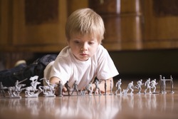 Closeup of a young boy playing with toy soldiers on floor