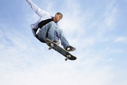 Low angle view of young man on skateboard in midair against cloudy sky