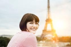 Portrait of a happy young woman smiling in front of Eiffel Tower
