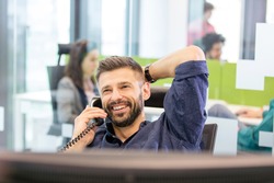 Smiling mid adult businessman talking on phone in office