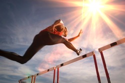 Runner jumping over running hurdle, low angle view