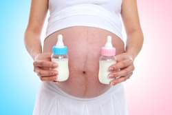 A pregnant woman mother holding baby bottles for twins