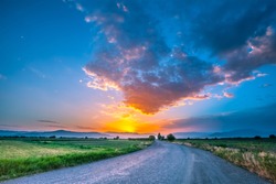 magnificent landscape of road on meadow on background of beautiful sunset sky with clouds