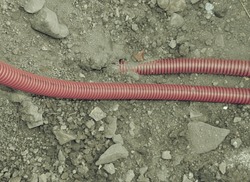 Safety tube with cables. Reconstruction site with trench for underground telephone optical lines