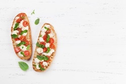 Caprese bruschetta toasts with mozzarella, cherry tomatoes and fresh garden basil. Top view with space for your text