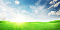 Green grass field and blue sky with bright sun summer landscape background