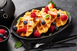 Delicious belgian waffles with ice cream and summer berries and breakfast tea