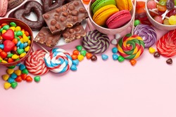 Various sweets assortment. Candy, bonbon and macaroons on pink background. Top view with copy space