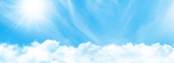 Blue sky with light clouds and bright sun. Wide summer sky backdrop