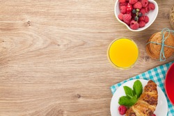 Healthy breakfast with muesli, berries, orange juice, coffee and croissant. View from above on wooden table with copy space