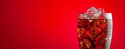 Cola beverage with ice. Fresh cold sweet drink with ice cubes. Over red background with copy space