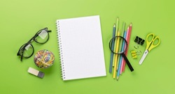 School supplies and stationery on green background. Flat lay with blank space