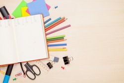 Blank notepad over school and office supplies on office table. Top view with copy space