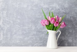 Fresh pink tulip flowers bouquet on shelf in front of stone wall. View with copy space