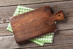 Cutting board over towel on wooden kitchen table. Top view