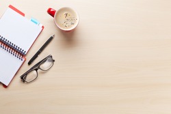 Office desk workplace with coffee cup, notepad and glasses on wooden background.  Top view with copy space 