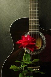 Red rose on a black acoustic guitar