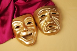 Comedy and tragedy masks with purple drapery on a yellow background. Theater symbol.