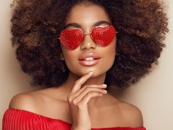 Beautiful portrait of an African girl in sunglasses in the shape of hearts. Valentine's Day. Symbol of love