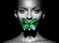 Fashion model woman in bright sparkles and lights posing in studio. Portrait of beautiful woman with butterfly. Art design glitter glowing make up. Black and white photography