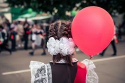 The last call at school. A teenage girl in school uniform with a red balloon in her hand.. Parade of schoolchildren, graduates with bright balloons colorful in hands.