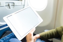 Young woman using tablet on plane