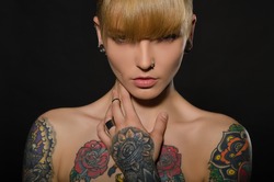 Beautiful blonde with a tattoo on body, dark background