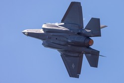 Very close tail view of a F-35 Lightning II  with afterburner on and condensation trails 