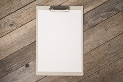 Clipboard with white sheet on wooden background