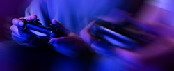 gamers playing console video games. controller in hands closeup. neon lights banner