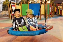 cheerful children having fun in playground basket swing