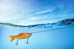 goldfish fishing lure underwater on blue sky background. copy space