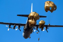 Group of military parachutist paratroopers jumping out of a military transport plane.