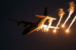 Military plane firing flares during a  night flight.
