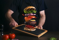 Man serving a delicious layered burger on a serving board