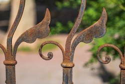 Close up of a detail of an old ornately forged rusted fence