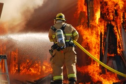 ROSEBURG, OR - SEPTEMBER 03: Single fire fighter spraying a straight steam into a fully involved shop fire off of Breezy Lane, September 03, 2011 in Roseburg, OR