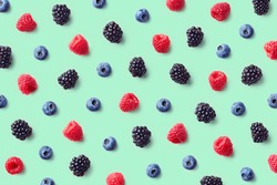 Colorful fruit pattern of wild berries on blue background. Raspberries, blueberries and blackberries. Top view. Flat lay