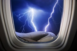 Photo of a lightning through a window in an airplane.