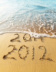 New Year 2012 is coming concept - inscription 2011 and 2012 on a beach sand, the wave is covering digits 2011.
