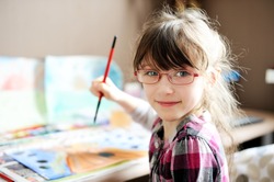 Cute little girl painting a picture in home studio