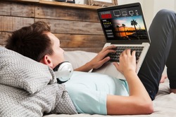 Man watching streaming series in a laptop computer, lying in the bed at home.
