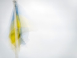 Ukraine national flag hanging in light breeze. Defocused Impressionist effect with copyspace.