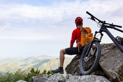 Mountain biker looking at view on bike trail in autumn mountains. Male rider resting on cycling trip in nature. Sport fitness, motivation and inspiration in beautiful inspirational landscape.