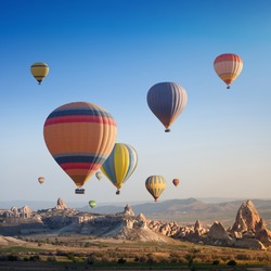 Hot air balloon flying above rocky landscape in Cappadocia, Turkey