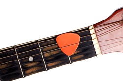 Orange guitar pick on the fingerboard