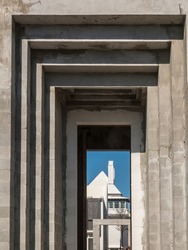 Perspective of passageway framed by tall flat concrete arches on the construction site of a tower in a tourist town along the Gulf Coast of Florida